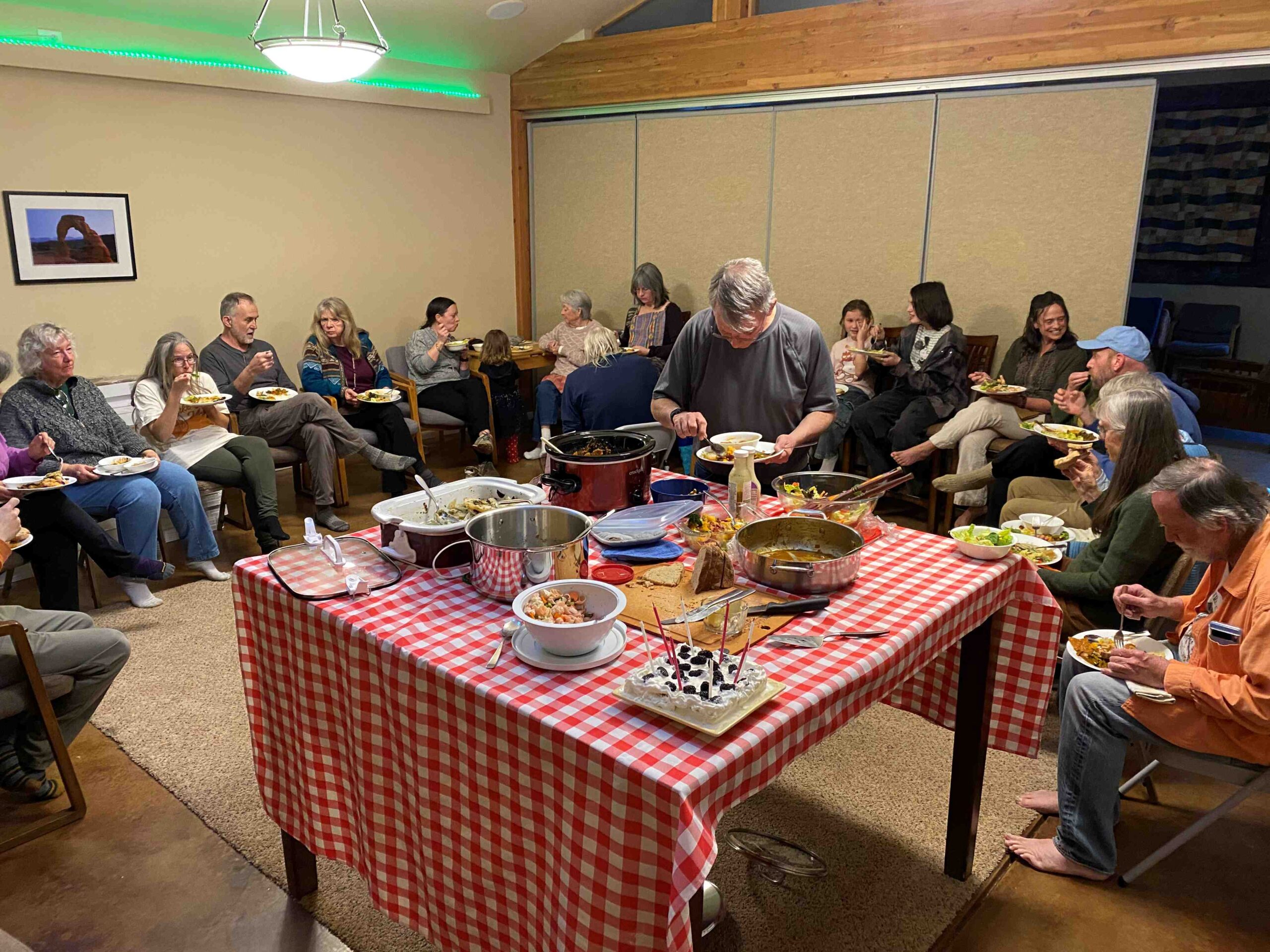 Potluck with table and folks eating all around 2025